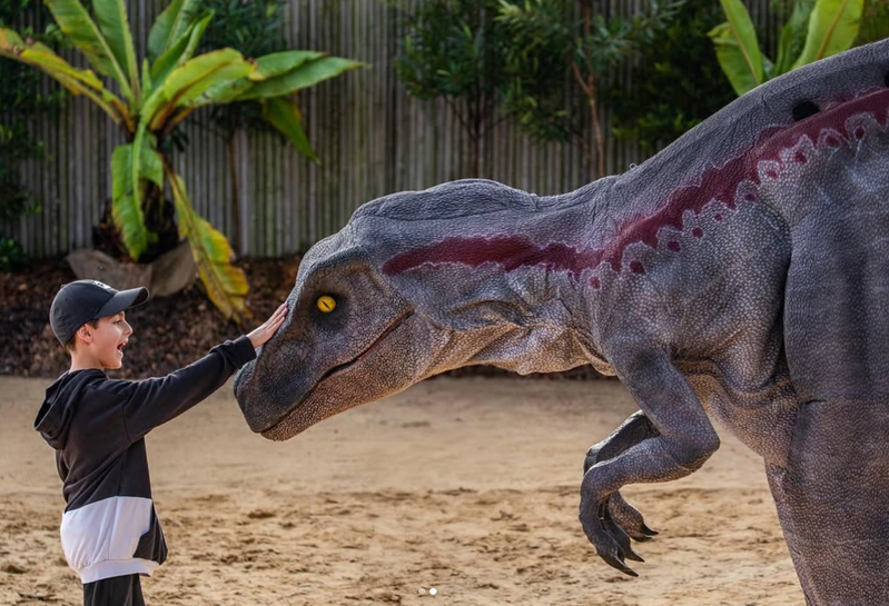Child meeting a life-sized roving dinosaur at DinosRoar